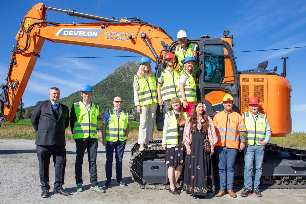 Gruppe i refleksvestar framfor ei gravemaskin